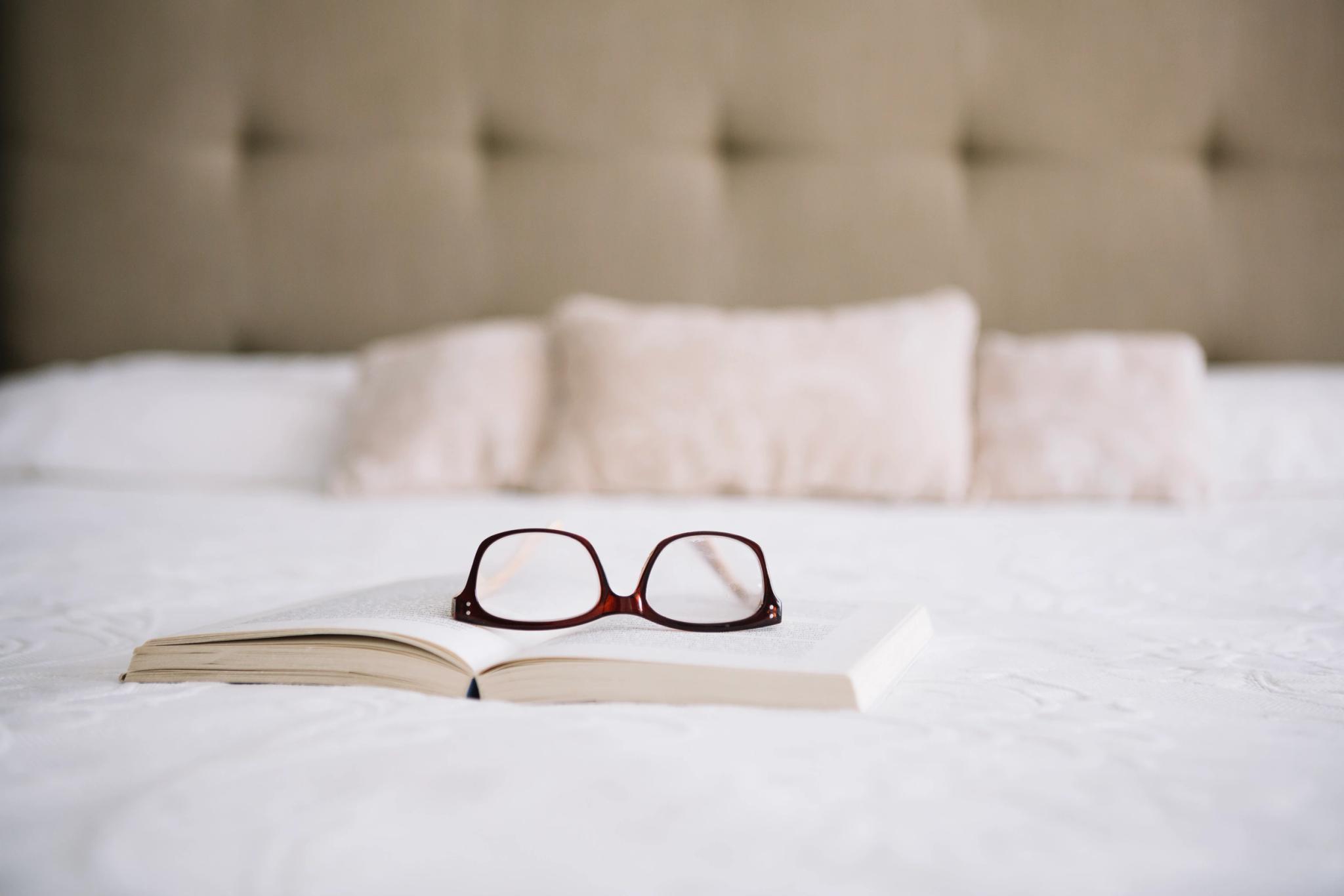 Livres et lunettes posés sur un lit dans une chambre de l'hôtel San Andrea